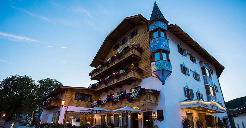 Hotel Enzian Genziana in der blauen Stunde mit beleuchteter Tiroler Fassade in Seis am Schlern