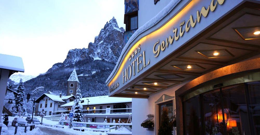 Eingang des Enzianhotels in Seis am Schlern im Winter – beleuchteter Hoteleingang mit Schnee, Seiser Alm